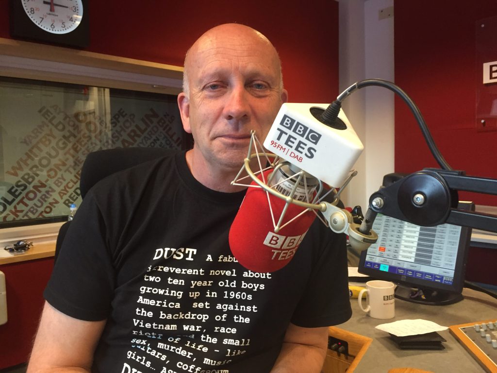 Mark Thompson in a radio studio. He sits in front of a BBC Tees microphone.