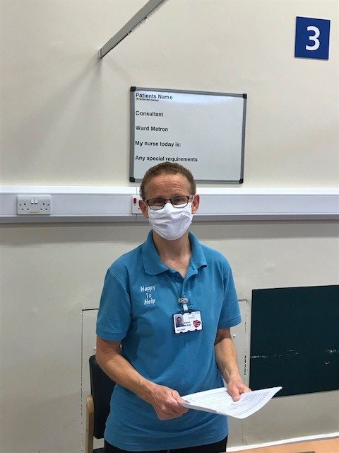 Alison McNab. She wears a face mask and carries paperwork.