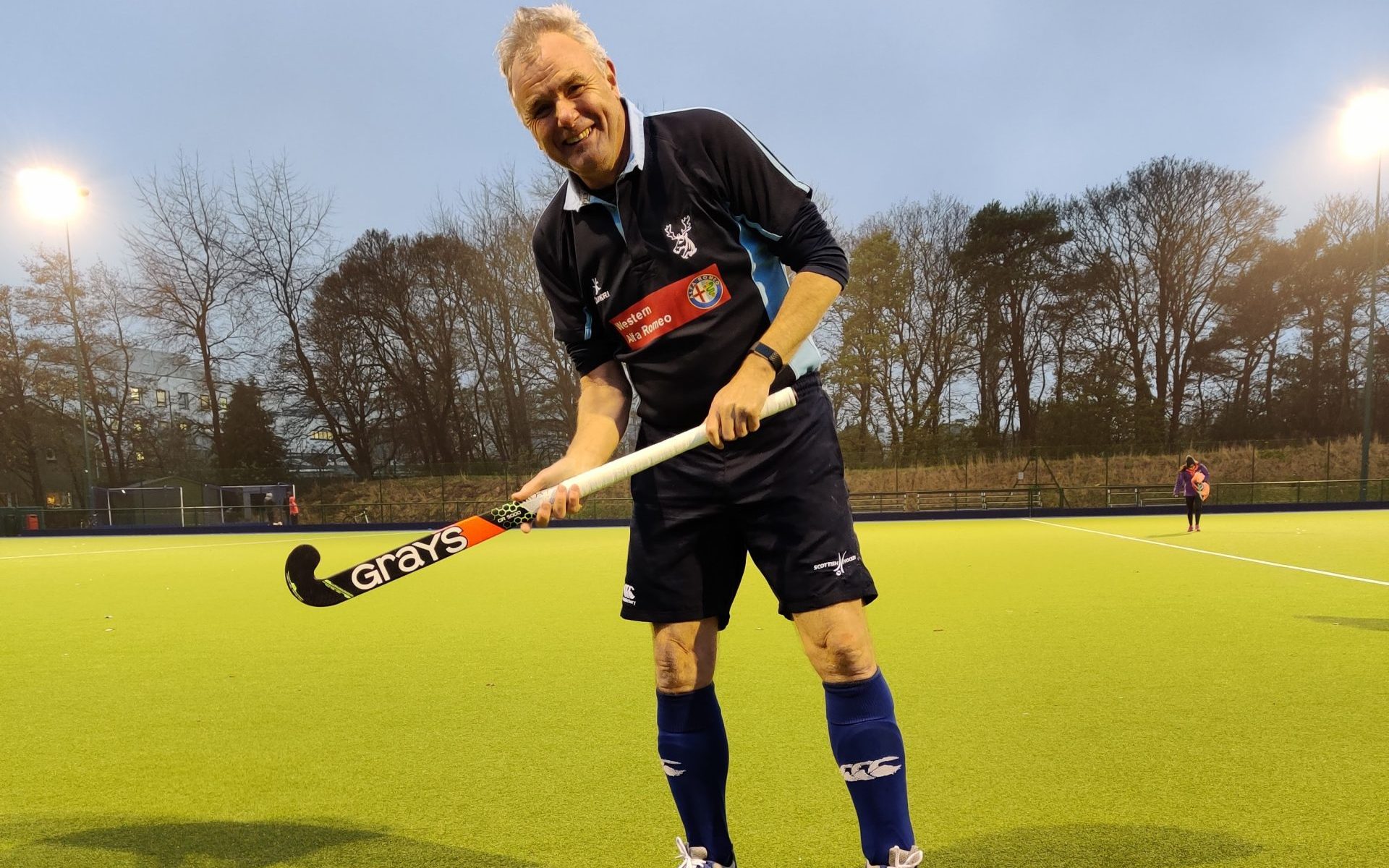 Derek Bell holding a hockey stick on a hockey pitch.