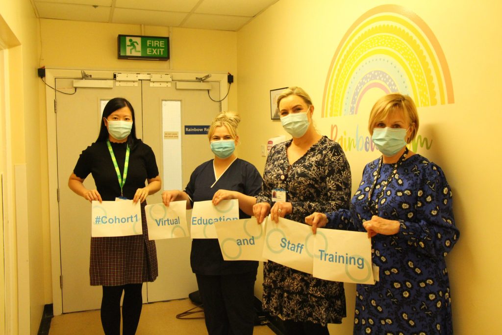 Jun Saw and some of her 100 Leaders pack. They hold signs reading: "#Cohort1 Virtual Education and Staff Training".