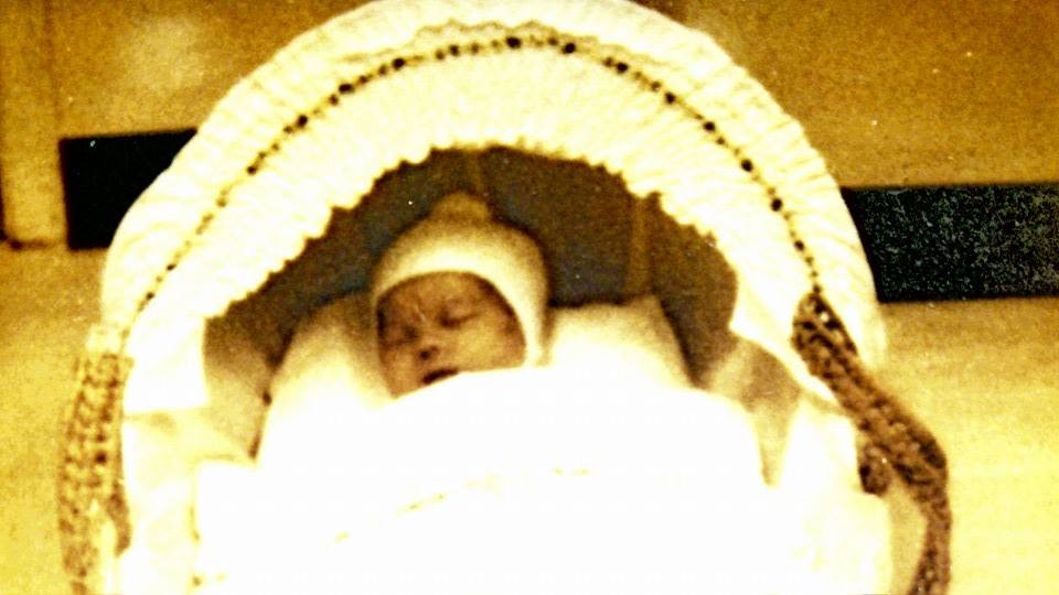 Samantha's brother Daniel as a baby. He lies in a cot.