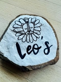 A rock painted white. A lion is painted on it and underneath it reads "Leo's".