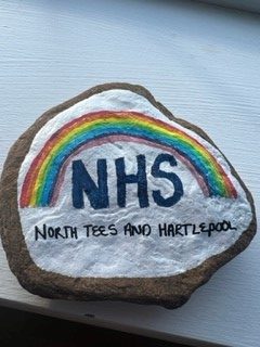 A rock painted white. There is a rainbow painted on it. Underneath it reads: "NHS North Tees and Hartlepool."