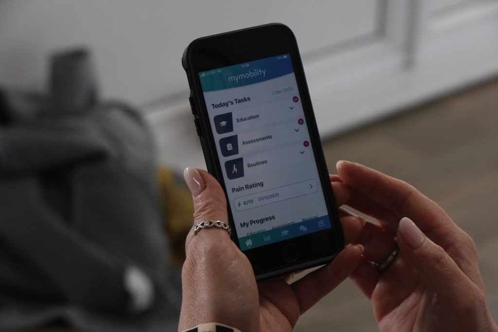A mobile phone with the app open. The app shows a header reading "Today's tasks" above dropdown icons which read "Education", "Assessments" and "Routines".