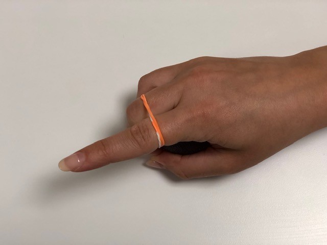 Hand strengthening image. Resistance ball being held and elastic band around fingers.