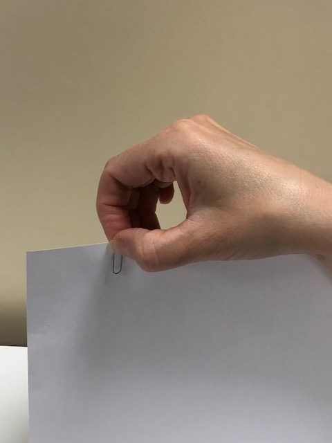 Piece of paper being pinched with thumb and first finger.