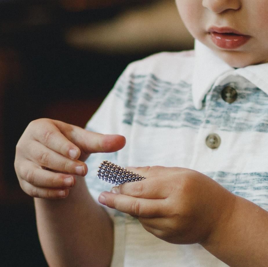 child holding beaded magnets