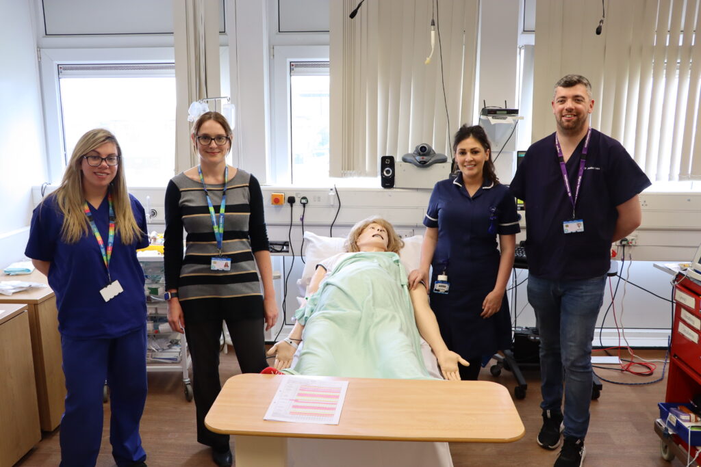 Colleagues who helped train and support medical students gathered round medical SIM Manikin