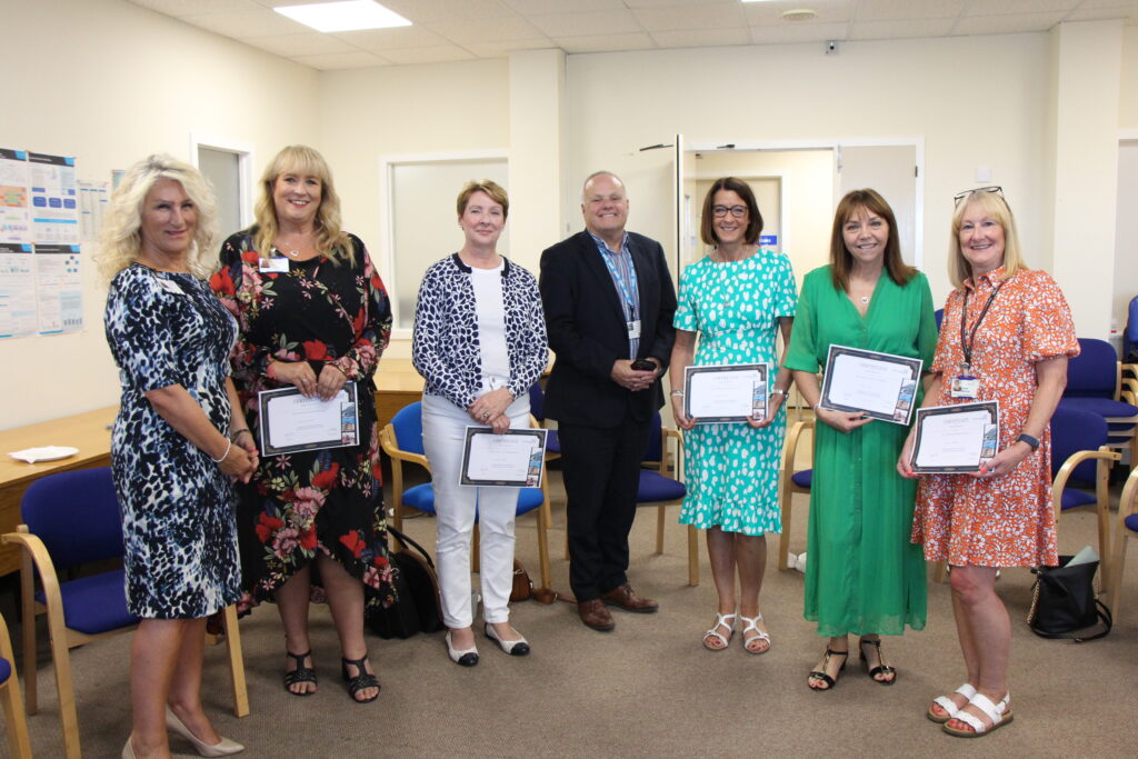 Staff group with long service awards stand with former non-executive Steve Hall and Chief Executive Julie Gillon.