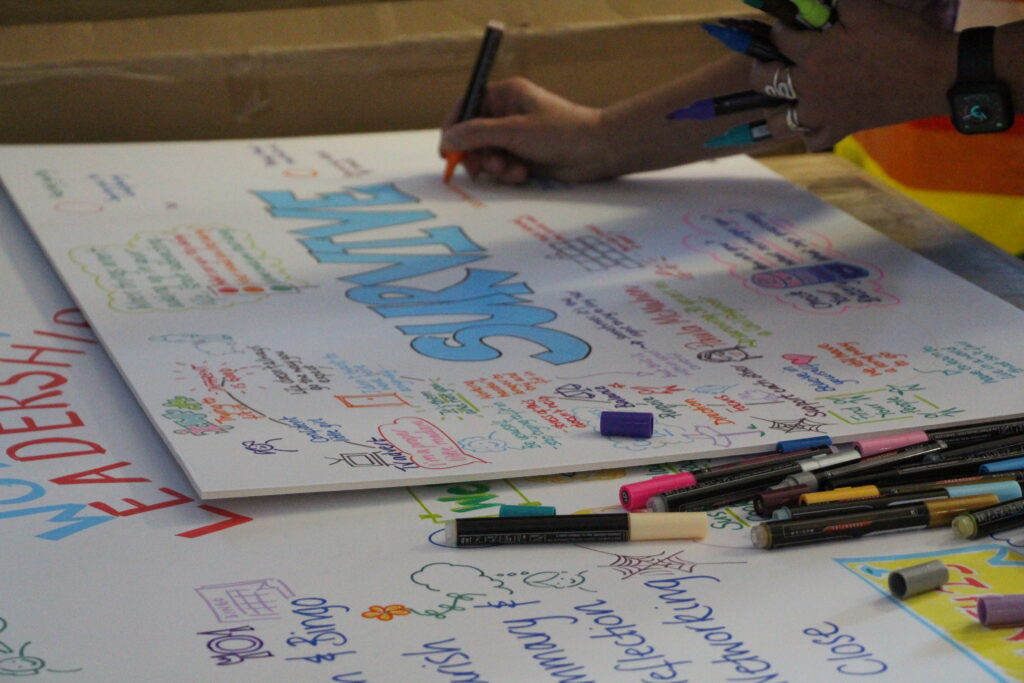 Someone draws images on a board that reads 'Survive'.