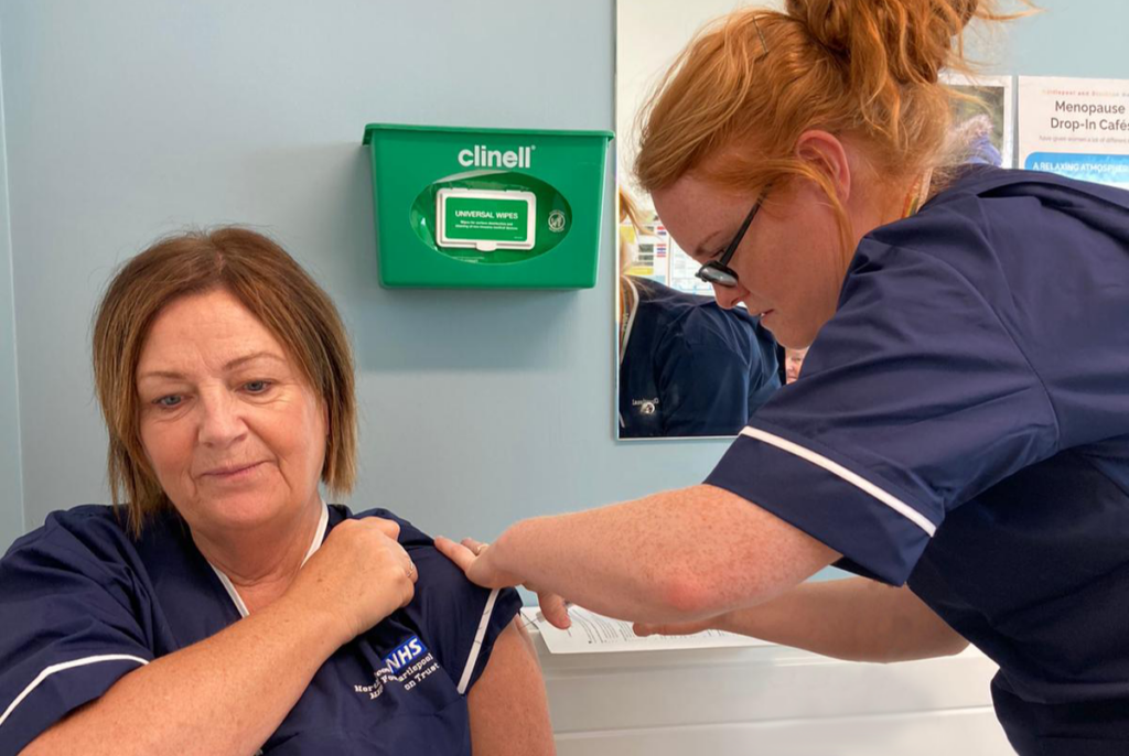 A nurse vaccinates a member of staff.