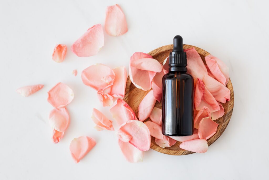 Aromatherapy - essential oil bottle surrounded by rose petals
