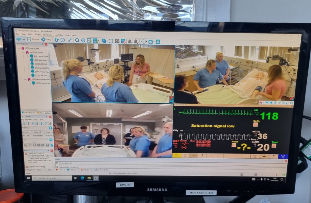 A live feed on a TV screen shows the training in progress.