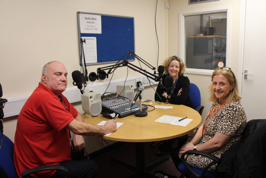 A podcast host sits opposite two guest speakers.