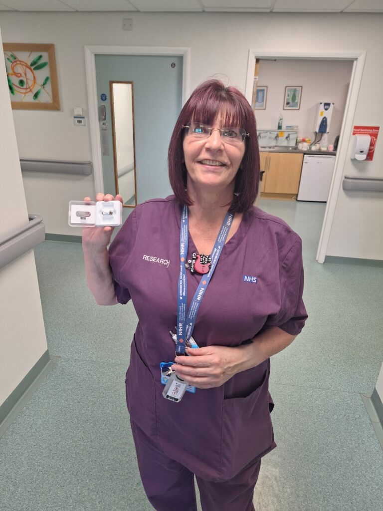 Nurse stood holding a capsule for a research study.