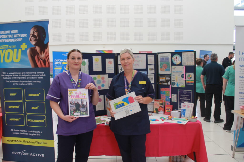 Staff hold leaflets and a Health and Wellbeing magazine.