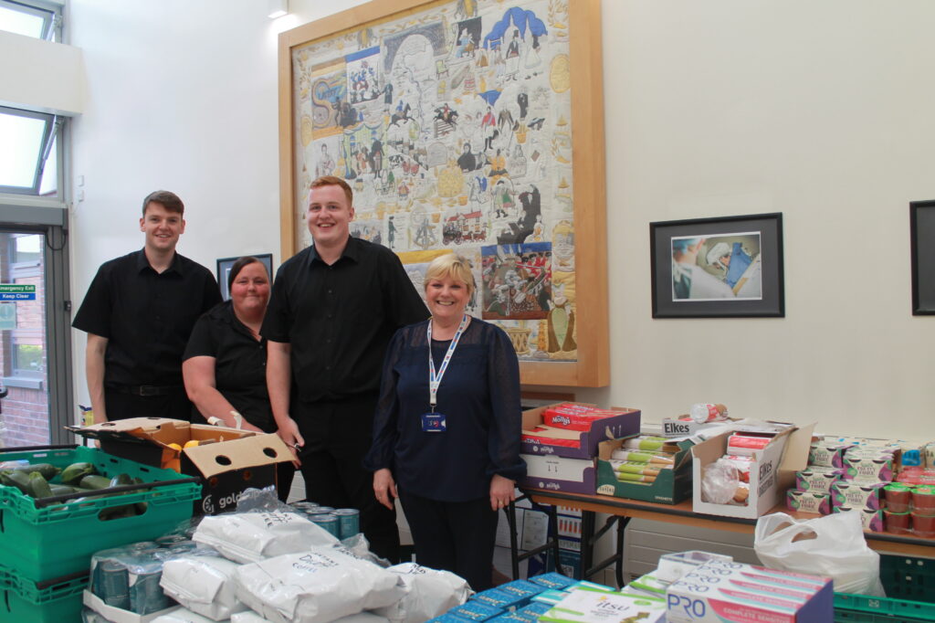 The eco shop team stand behind a table. On the table are food and hygiene products.
