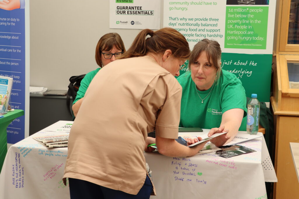 A member of staff discusses a leaflet with a stallholder.