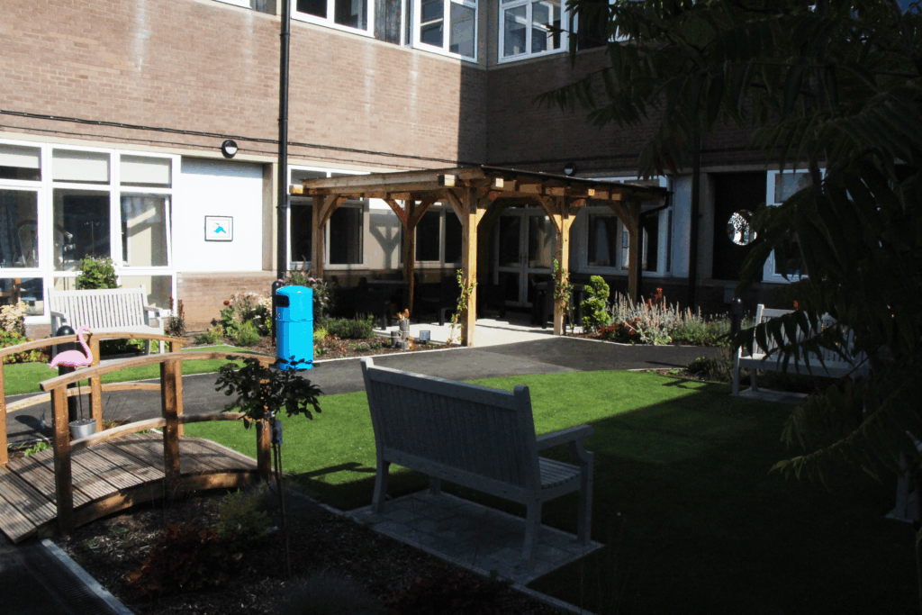 Kaleidostroke therapy garden, featuring a gazebo, bench, plants and grass area.
