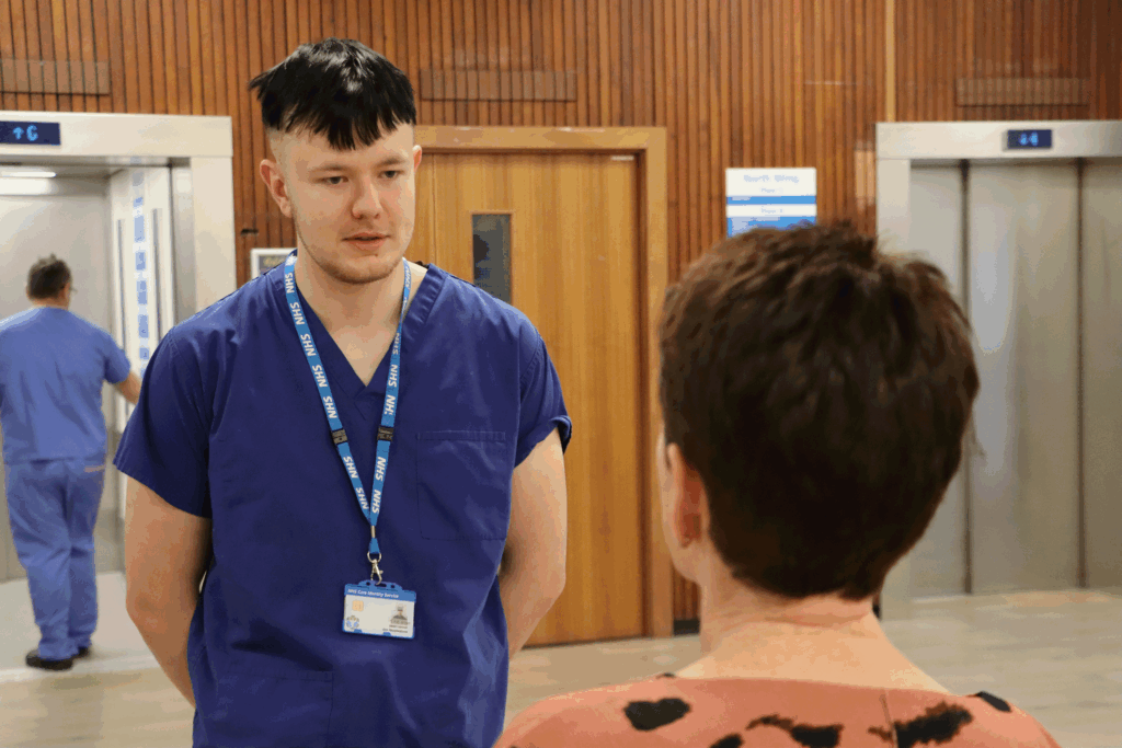 Joe talks to a patient in a corridor.