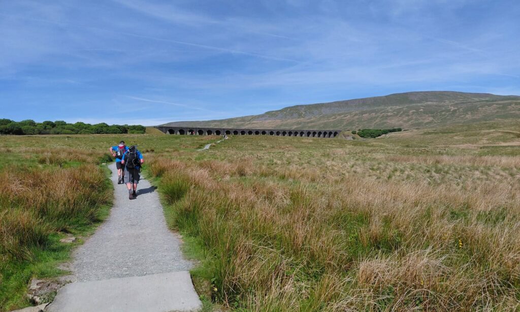 Two men walk in the countryside.
