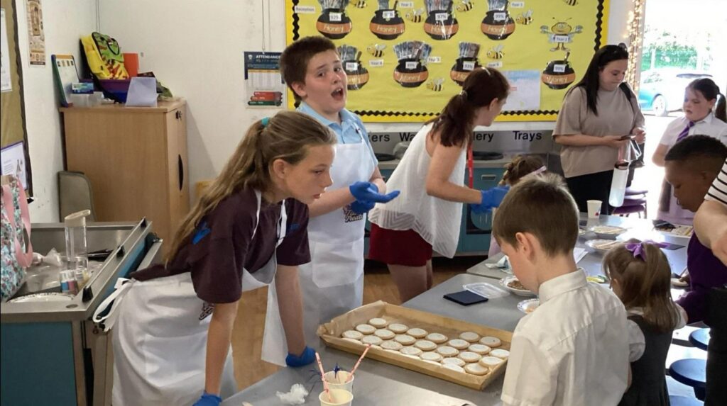 Children serve cakes and biscuits at a stall.