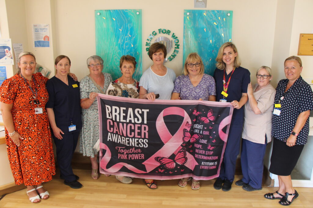 A group of women with nurses. They hold a banner which reads: "Breast cancer awareness. Together, pink power".
