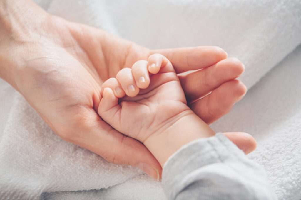 Mother's hand cradling the baby's hand.
