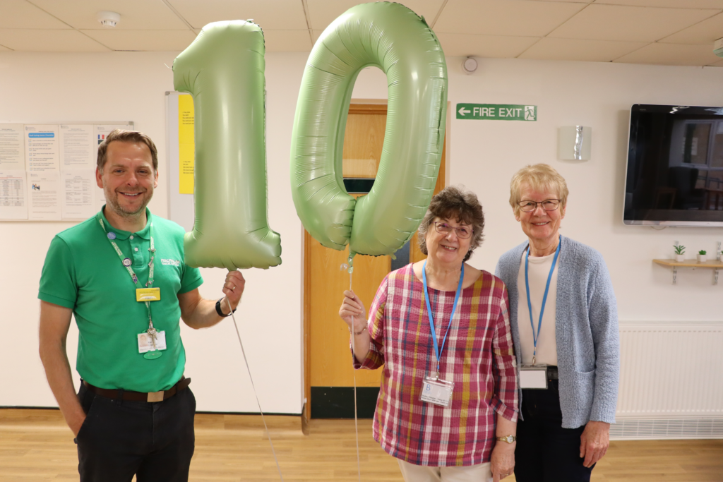 Alan Chandler, Mary Sayers and Carole Manton. They hold large green balloons spelling out '10'.