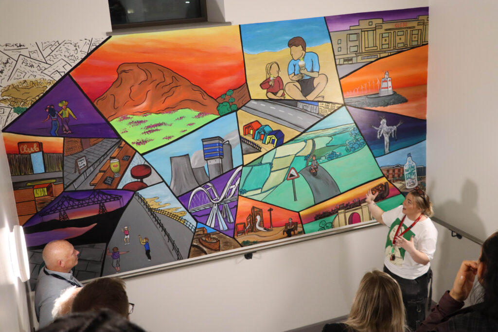 Artist Lily explains the community discussion and idea behind her second mural in the staff stairwell area.