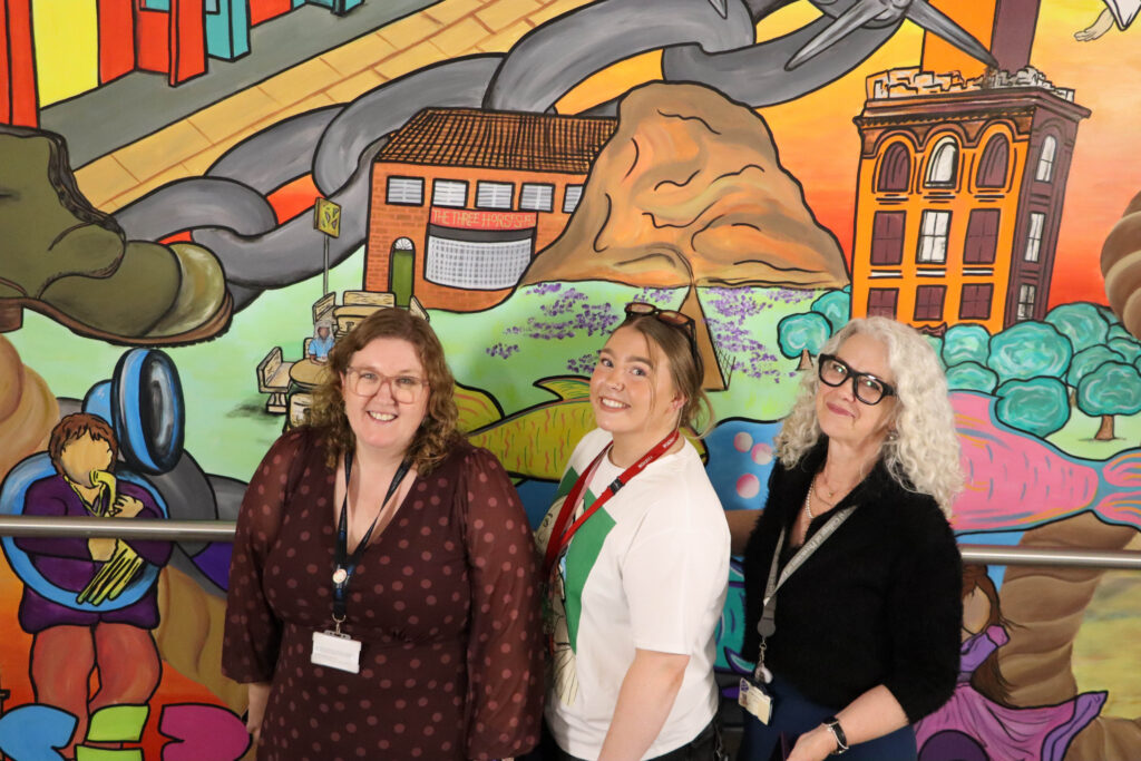 Jo-Anne Cole, Lily Rose Cockfield and Dr Jean MacLeod pose in front of one of the murals at the community diagnostic centre.