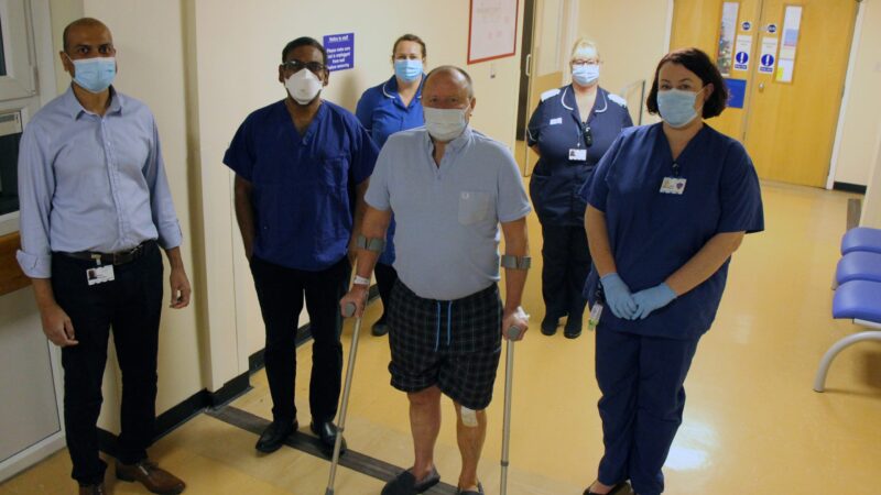 James O’Shea with Trust staff. James has a bandage on his knee and is holding crutches.