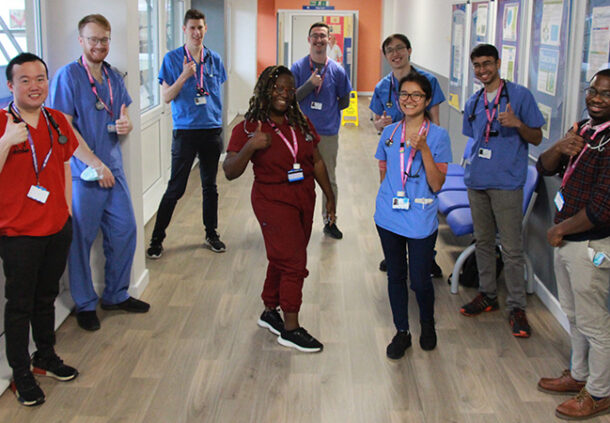 Doctors in training thumbs up in a corridor.
