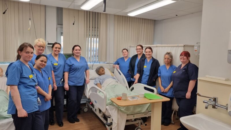 Nurses stand with a manikin in the simulation suite.