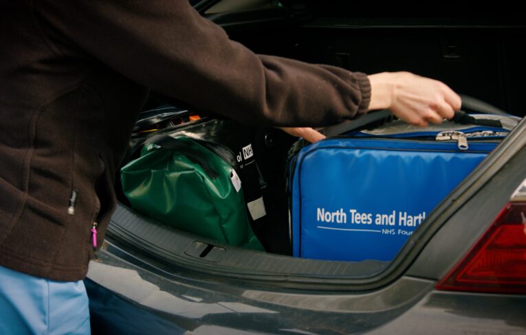 Hand of community nurse grabbing kitbag from car
