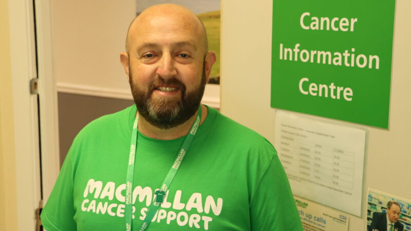 Cancer centre volunteer stood by information centre door