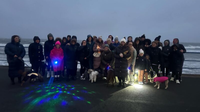 People standing on the seafront going on a baby loss walk.