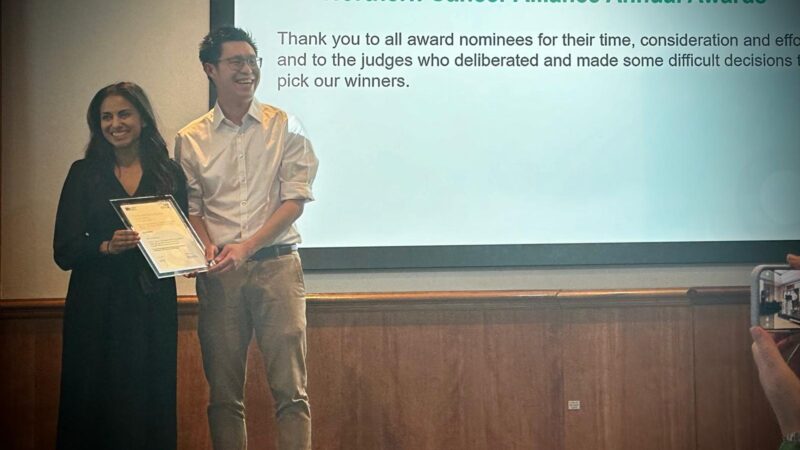 Two doctors stood on stage holding up an award.