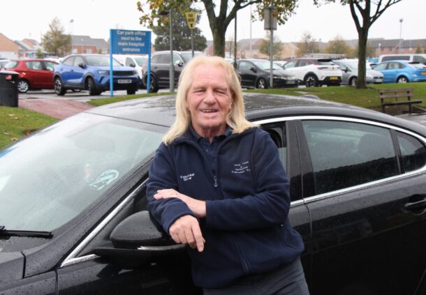 Robbie Earl leans on a car.