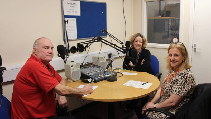 A podcast host sits opposite two guest speakers.