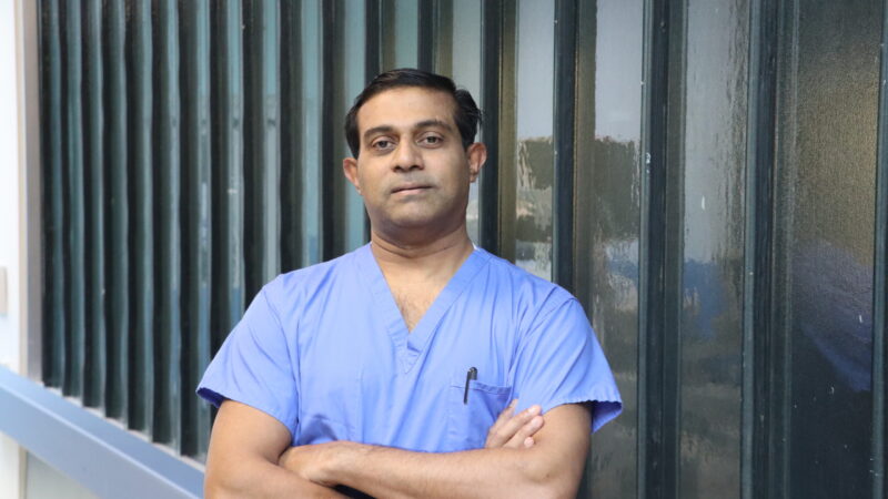 Man standing in corridor in scrubs for a photo.