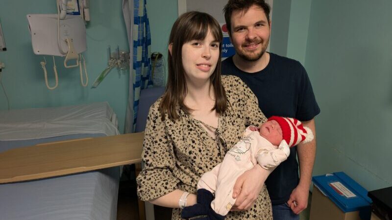 Parents holding their newborn baby for a photo.
