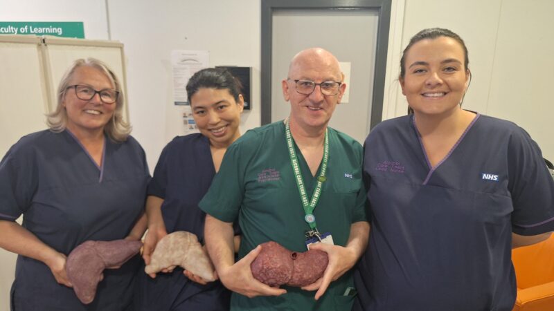 Liver specialist team standing together with information about liver health.