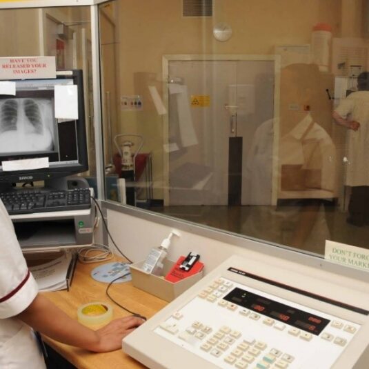 a staff member stands behind an x-ray shield while performing x-ray on patient