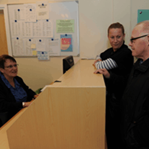 Patient and carer talk with staff member who is helping to book an appointment.
