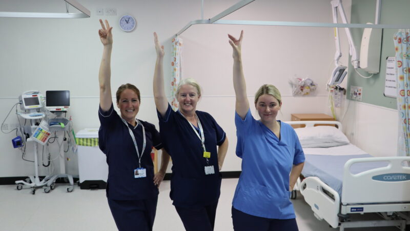 The North Tees children's nurses. They pose with one hand in the air and one hand on their hips.