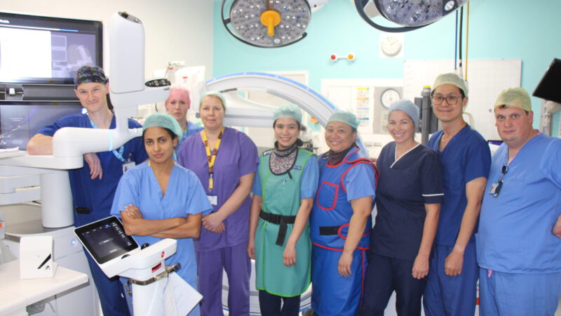 Theatre staff stand with the robotic bronchoscope.