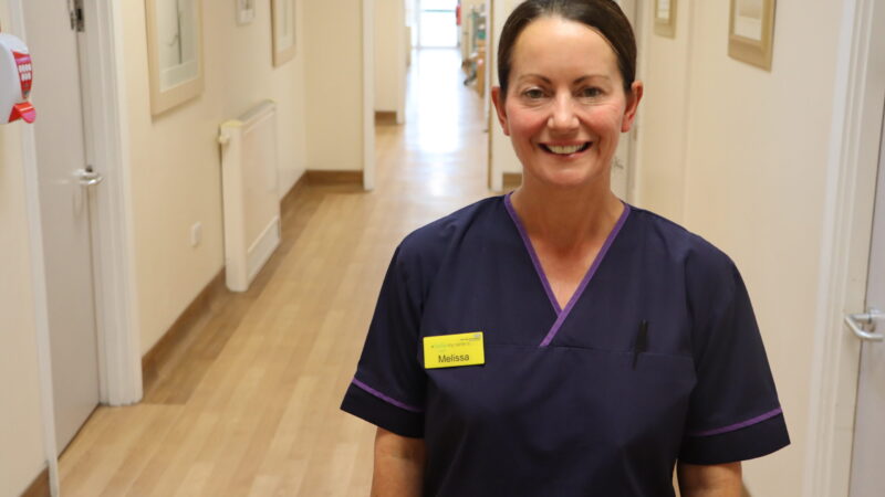 Breast nurse stands in corridor.