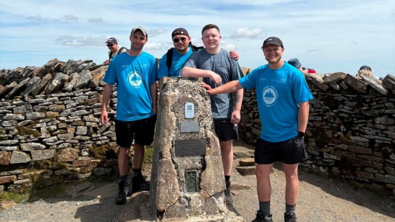 Four men stand on top of a mountain.