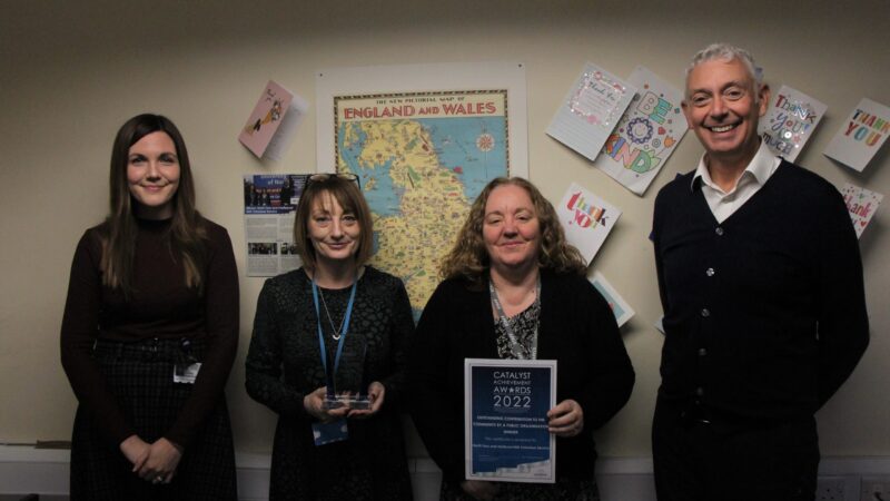 Group photo of the volunteer coordination team. One of the team holds their Catalyst trophy. Another holds their certificate.